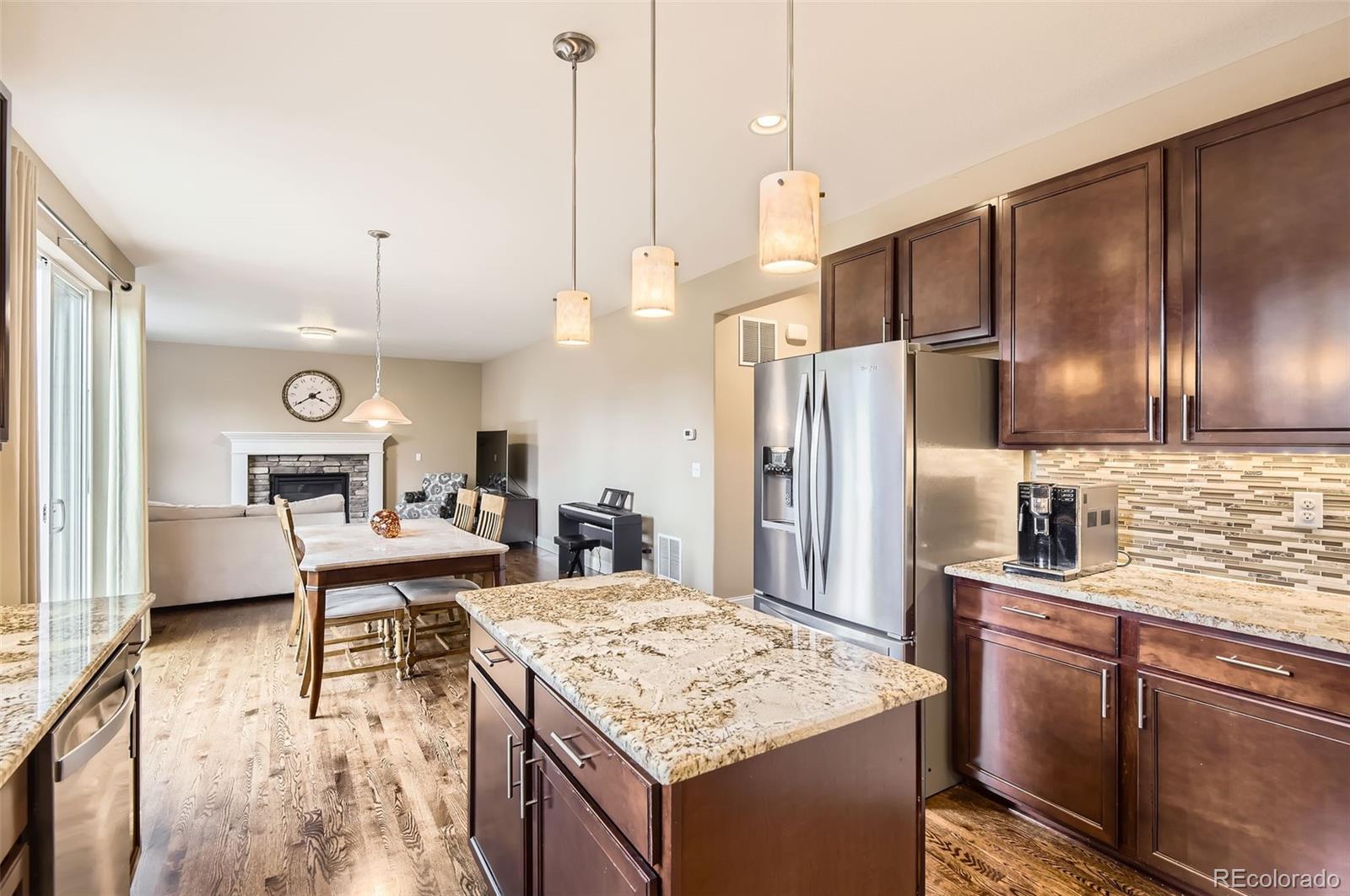 14110 Greenfield Loop Parker, CO 80134 - Photo 12 of 47 a kitchen with stainless steel appliances kitchen island granite countertop a refrigerator a stove and a sink with wooden floor