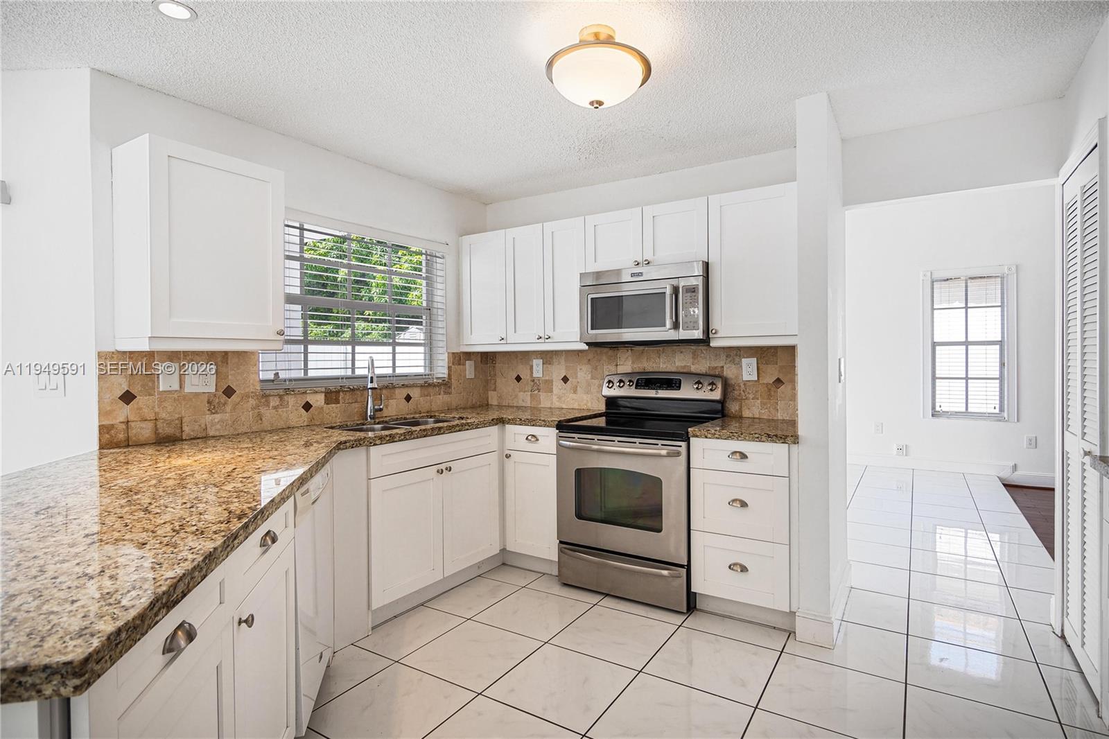14340 Southwest 90th Street Miami, FL 33186 - Photo 12 of 34 a kitchen with granite countertop white cabinets stainless steel appliances a sink and a window