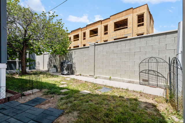 150 West 7500th South, Unit 13 Midvale, UT 84047 - Photo 32 of 32 Private backyard space featuring a concrete block perimeter wall, a mature tree, a paved patio area, and stepping stones