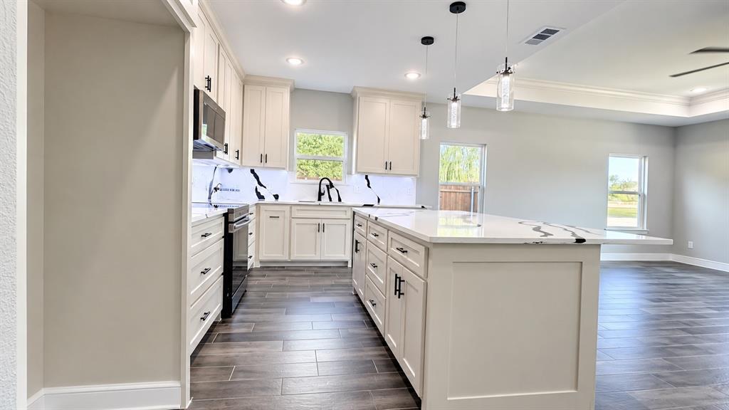 302-304 West Pine Street Whitewright, TX 75491 - Photo 18 of 38 Kitchen featuring an expansive island with a white countertop, cream cabinetry, a black faucet, and wood-look flooring