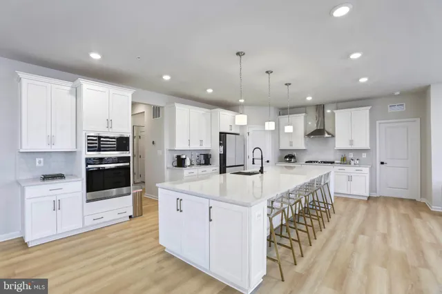 a large white kitchen with kitchen island a sink a center island stainless steel appliances and a cabinets