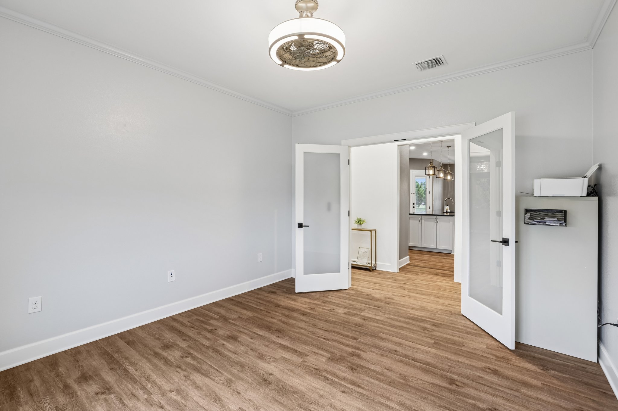 113 Crystal Lane Georgetown, TX 78633 - Photo 23 of 32 Rich hardwood-style flooring extends through this flexible room, featuring a sleek modern light fixture and frosted glass doors.