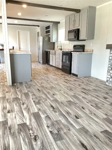 a kitchen with kitchen island granite countertop a refrigerator oven a sink dishwasher and white cabinets with wooden floor