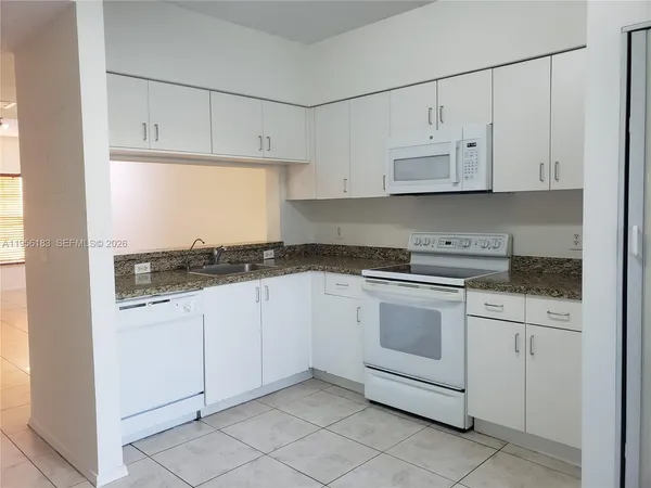 a kitchen with granite countertop white cabinets and white appliances