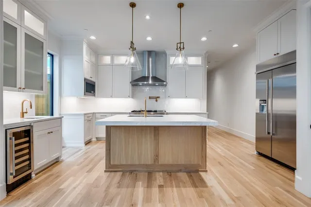 a large kitchen with granite countertop a large counter top a sink stainless steel appliances and cabinets