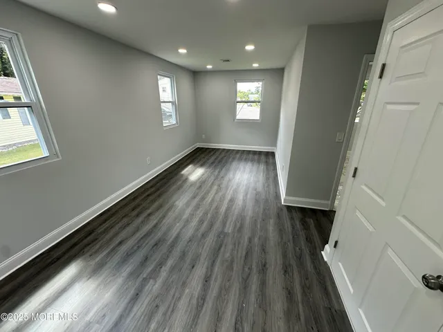 a view of hallway with window and wooden floor