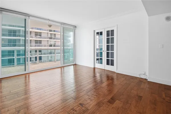 a view of an empty room with wooden floor and windows