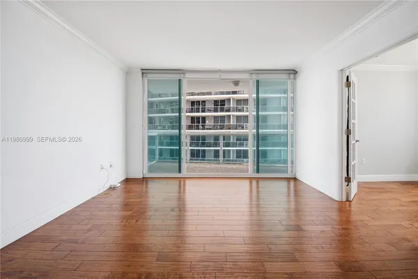a view of an empty room with wooden floor and windows