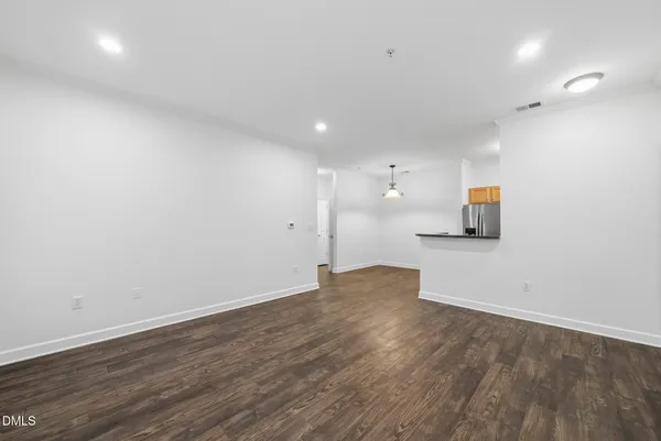 a view of an empty room with wooden floor and windows