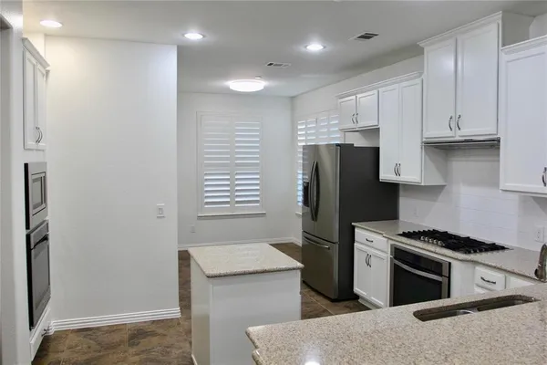 a kitchen with granite countertop a refrigerator and a stove top oven