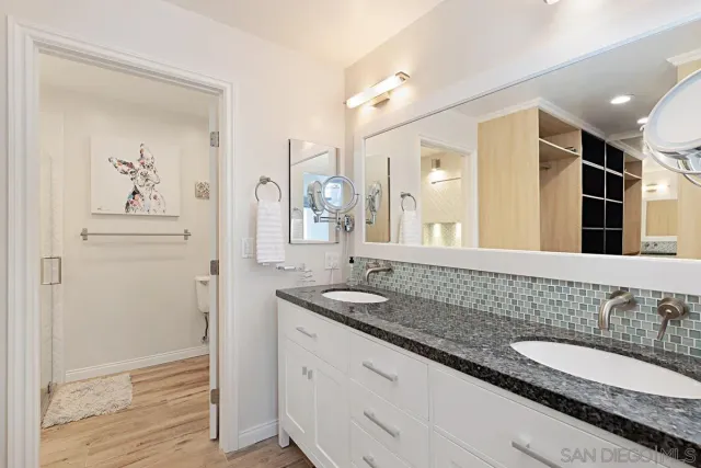 a bathroom with a granite countertop double vanity sink and a mirror