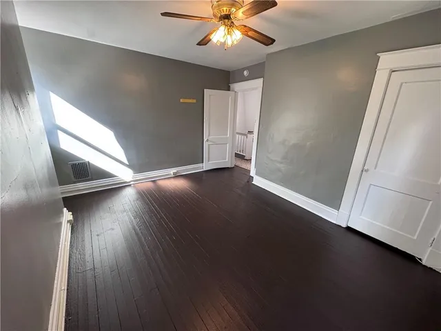 an empty room with wooden floor fan and windows