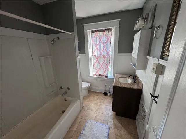 a bathroom with a granite countertop bathtub shower sink vanity and toilet