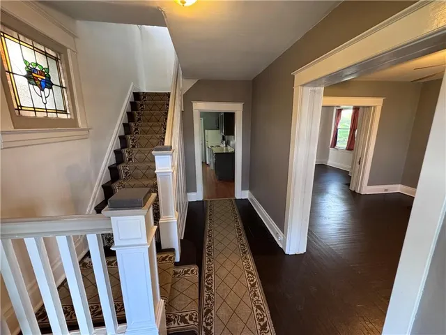 a view of a hallway with wooden floor and staircase