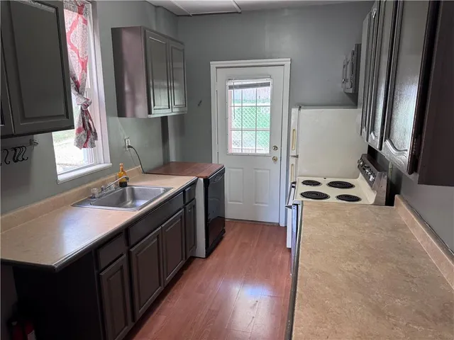 a kitchen with a sink a stove top oven and wooden floor