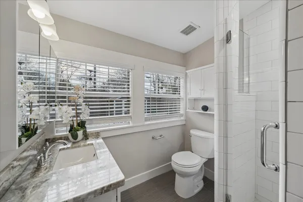 a bathroom with a granite countertop sink toilet and shower