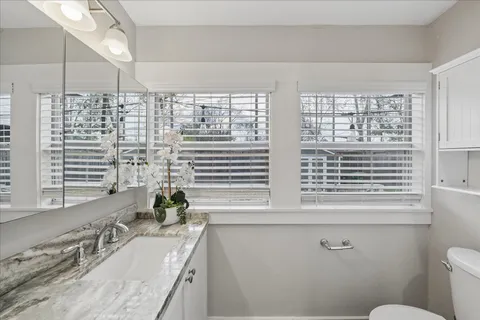 a bathroom with a granite countertop sink a large mirror and a window