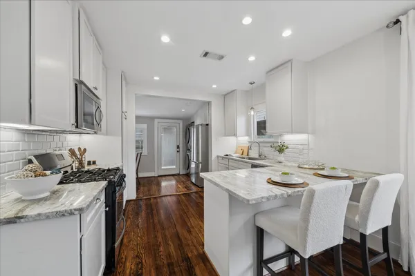 a kitchen with a dining table chairs stove refrigerator and microwave