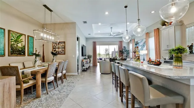 a dining room with stainless steel appliances kitchen island granite countertop a table chairs and a view of living room
