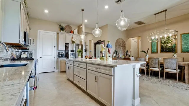 a kitchen with stainless steel appliances kitchen island granite countertop a table chairs sink and cabinets