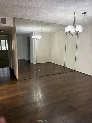 an empty room with wooden floor chandelier and entryway
