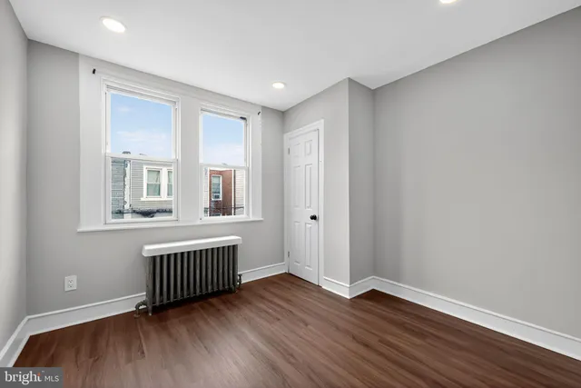 a view of an empty room with wooden floor and windows
