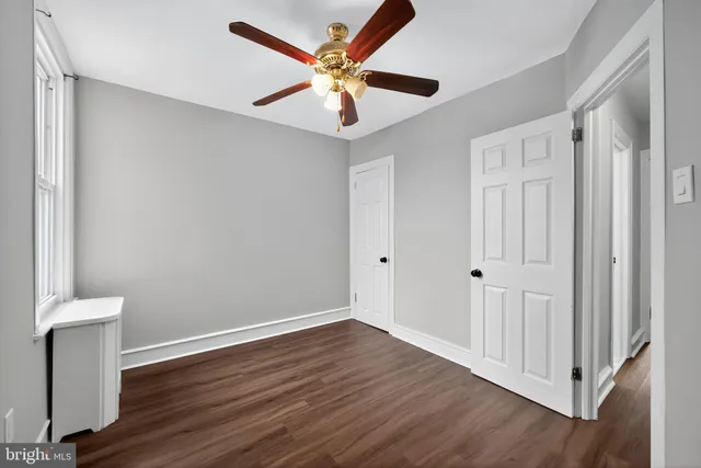 an empty room with wooden floor and a ceiling fan