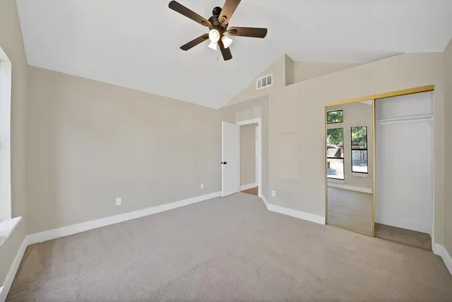 an empty room with windows and ceiling fan