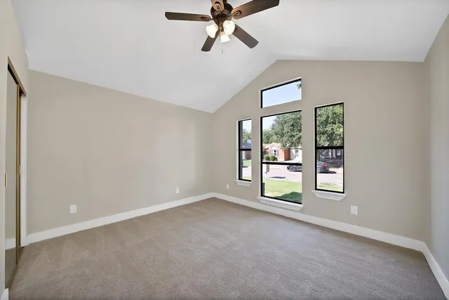 an empty room with windows and ceiling fan