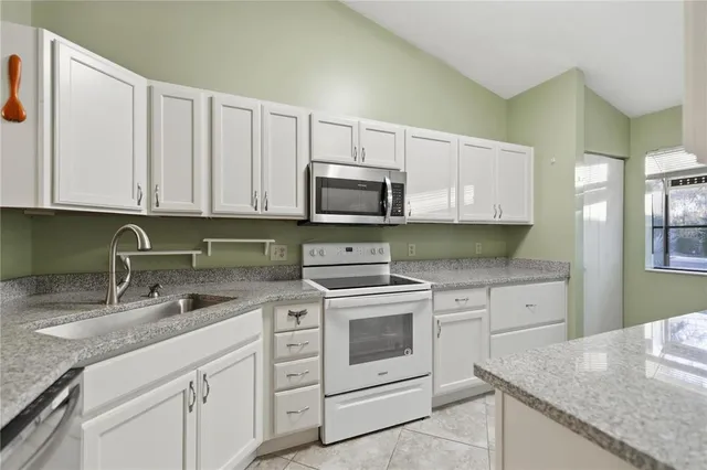 a kitchen with granite countertop white cabinets sink and stainless steel appliances