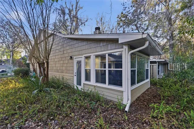 a view of a house with a small yard and large trees