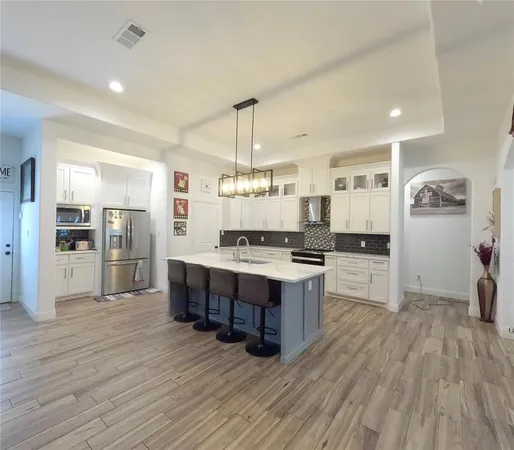 a large kitchen with a center island wooden floor stainless steel appliances and windows