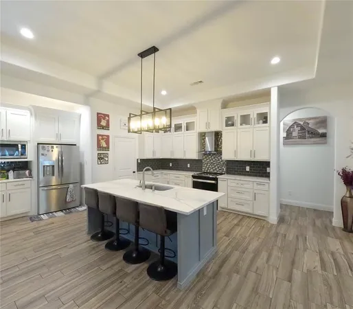a large kitchen with a center island wooden floor stainless steel appliances and cabinets