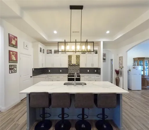a kitchen with stainless steel appliances kitchen island granite countertop a dining table chairs and wooden floor
