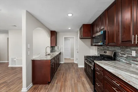 a kitchen with stainless steel appliances granite countertop wooden cabinets a stove top oven a sink and dishwasher