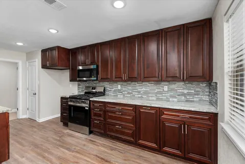 a kitchen with stainless steel appliances granite countertop wooden cabinets a stove top oven a sink and dishwasher