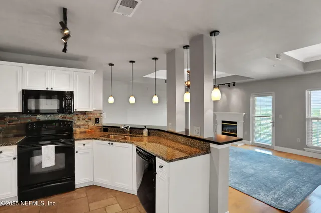 a kitchen with granite countertop a sink a counter top space and cabinets