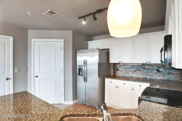 a view of a kitchen with a refrigerator and wooden floor