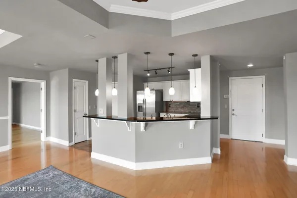 an empty room with chandelier fan and windows