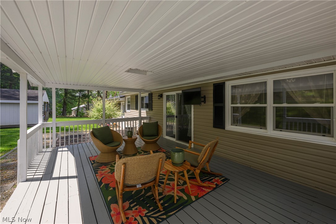 6105 Wolf Run Road Southeast Dennison, OH 44621 - Photo 12 of 35 Covered deck featuring a white vinyl ceiling, painted wood flooring, and white railings