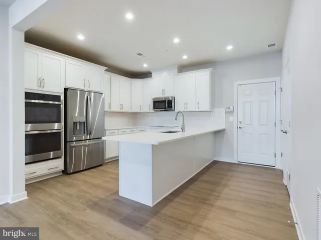 a kitchen with granite countertop white cabinets stainless steel appliances and a counter space