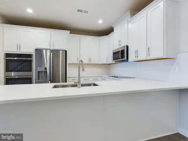 a kitchen with stainless steel appliances granite countertop a refrigerator sink and white cabinets