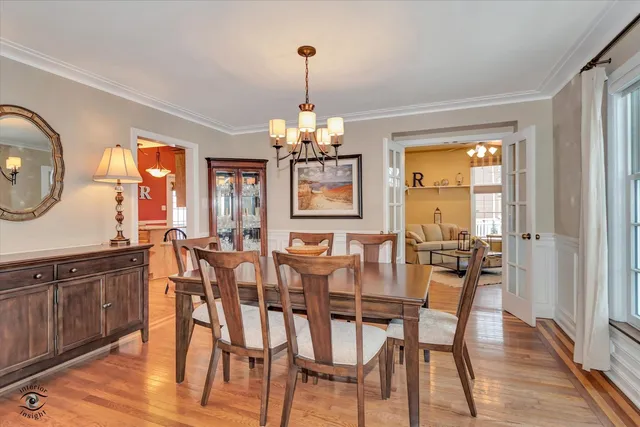 a dining room with wooden floor a chandelier a wooden table and chairs