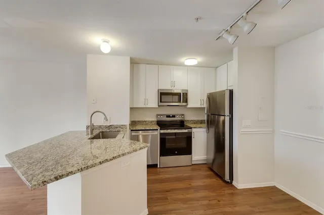 a kitchen with stainless steel appliances granite countertop a refrigerator a sink a stove a microwave and island