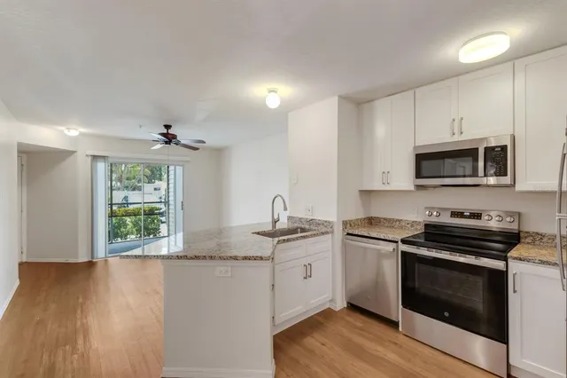 a kitchen with kitchen island white cabinets a sink a window and appliances