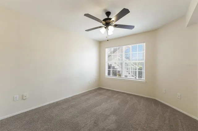 an empty room with windows and fan