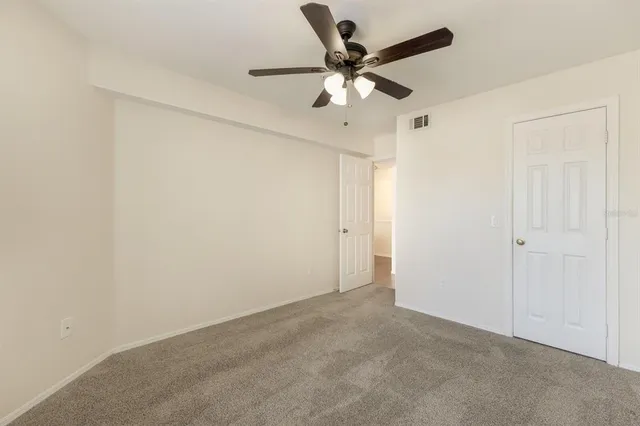 an empty room with a window and a ceiling fan