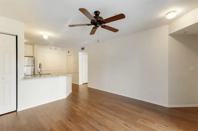 a view of empty room with wooden floor and ceiling fan