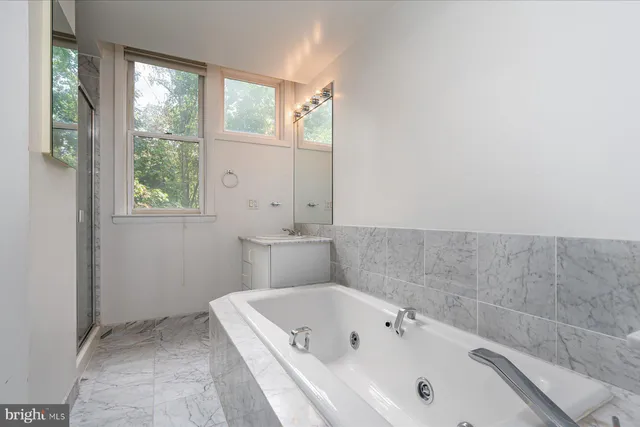 a bathroom with a tub a sink and a window
