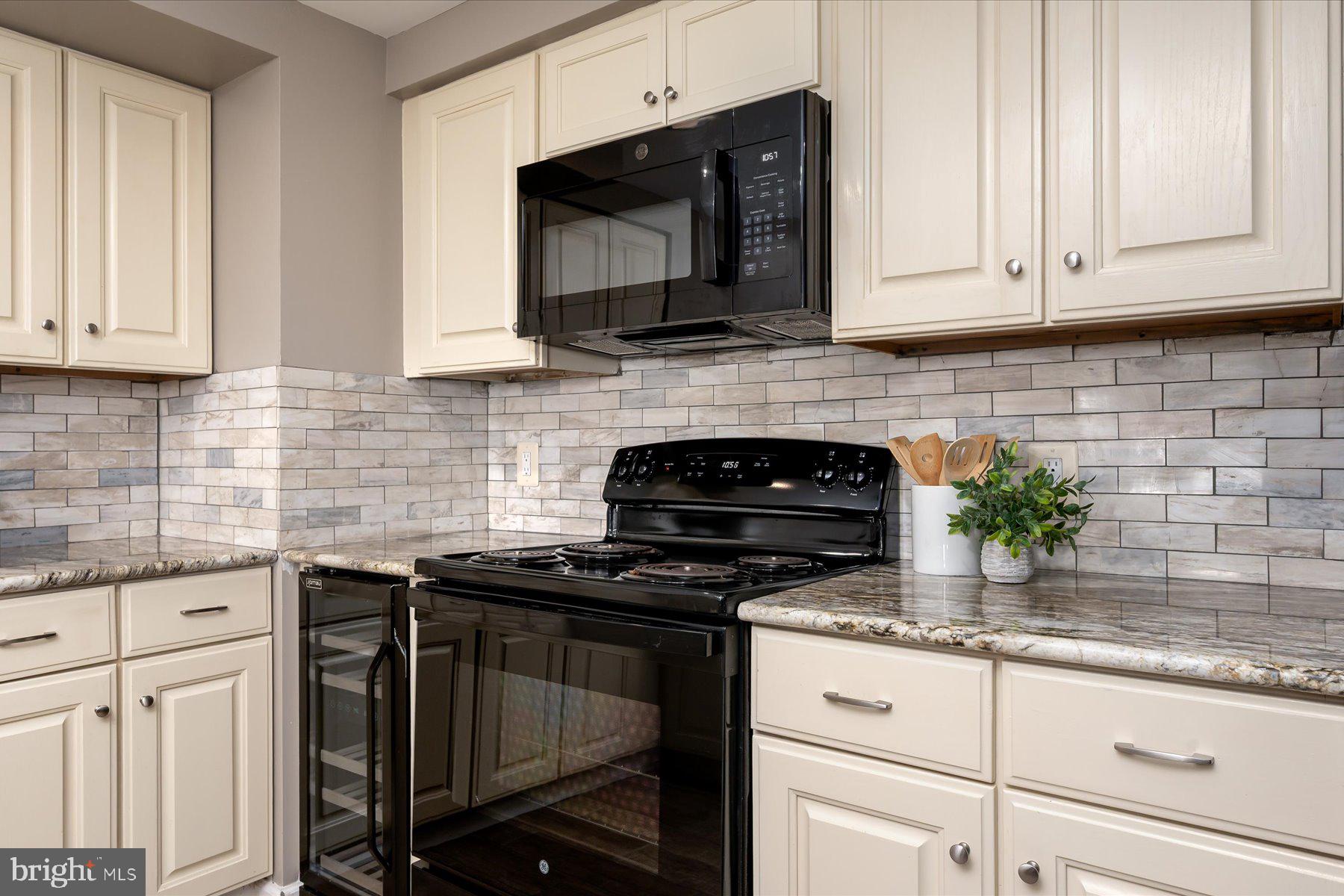930 Astern Way, Unit 405 Annapolis, MD 21401 - Photo 7 of 27 a kitchen with granite countertop white cabinets appliances a potted plant and a window